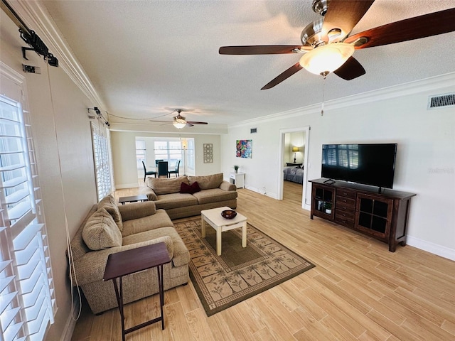 living room with ornamental molding, ceiling fan, a textured ceiling, and light hardwood / wood-style floors