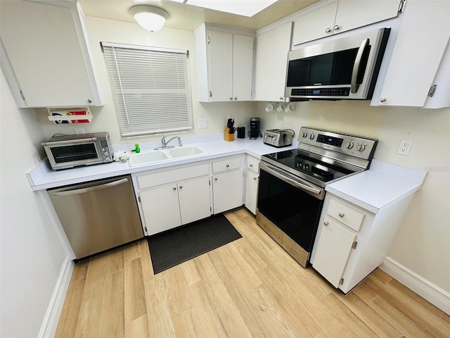 kitchen featuring white cabinetry, sink, stainless steel appliances, and light wood-type flooring