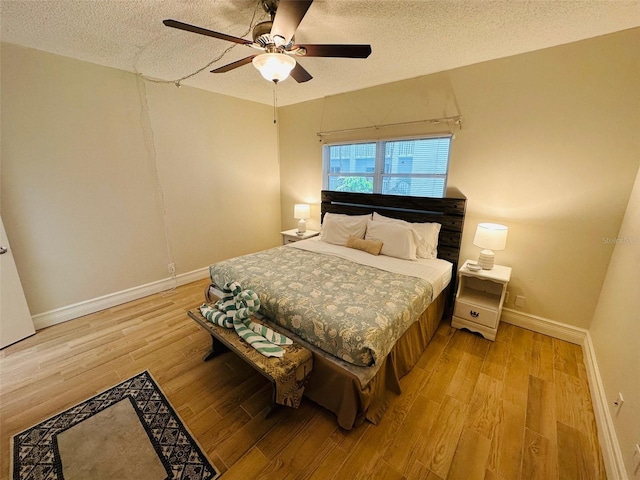 bedroom featuring light wood-type flooring, a textured ceiling, and ceiling fan