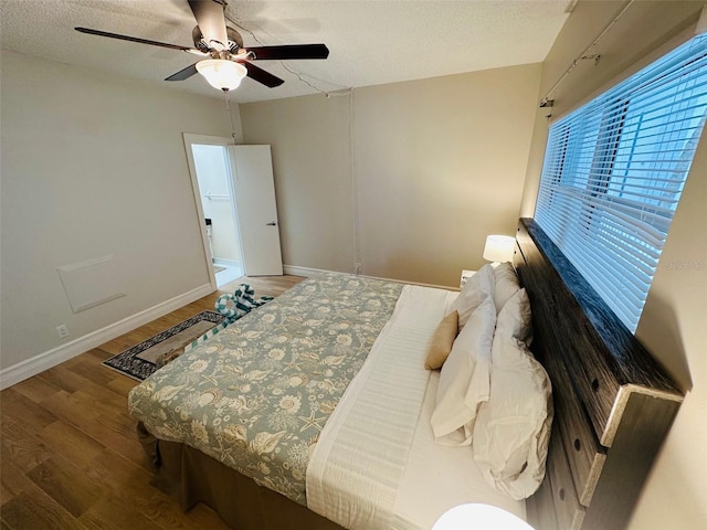 bedroom with hardwood / wood-style flooring, a textured ceiling, and ceiling fan