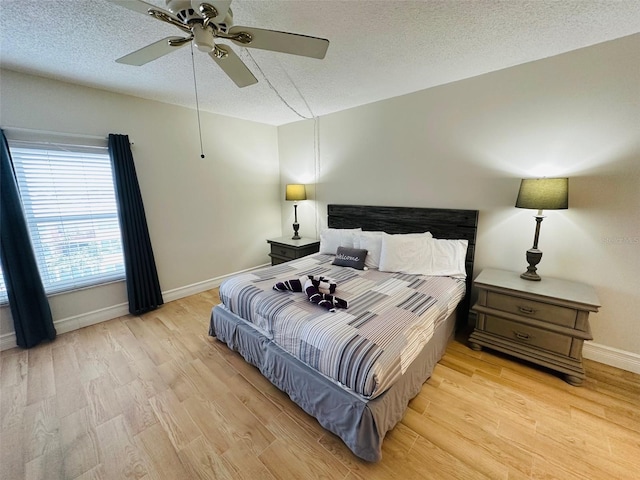 bedroom with lofted ceiling, a textured ceiling, ceiling fan, and light hardwood / wood-style floors