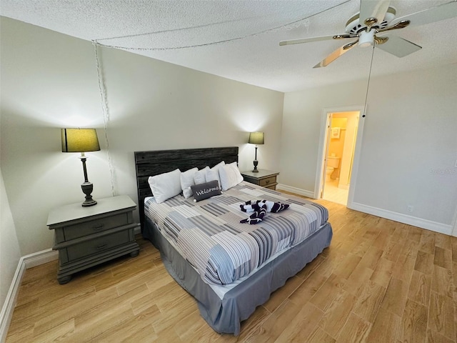 bedroom with ceiling fan, connected bathroom, light hardwood / wood-style flooring, and a textured ceiling