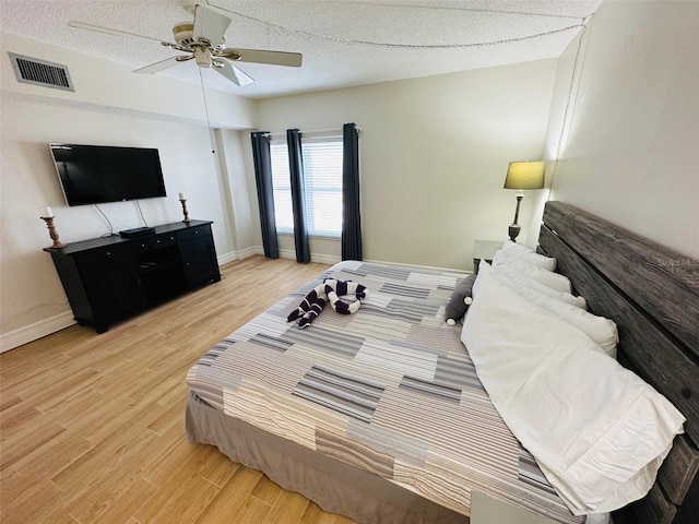 bedroom featuring ceiling fan, a textured ceiling, and light wood-type flooring