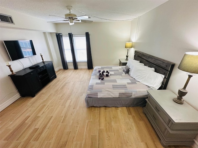 bedroom with ceiling fan, a textured ceiling, and light wood-type flooring