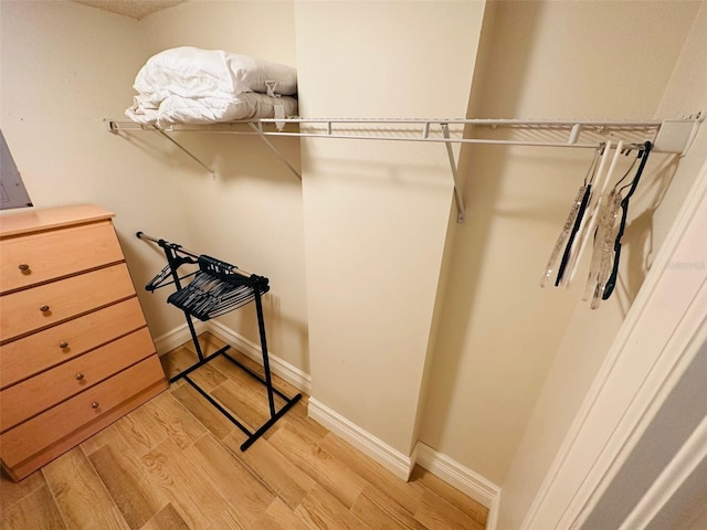 walk in closet with light hardwood / wood-style flooring