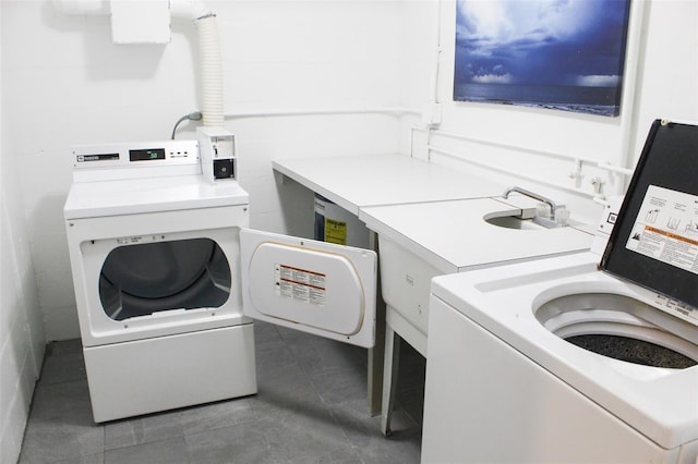 laundry area featuring washer and clothes dryer and dark tile patterned floors