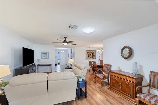 living room with ceiling fan with notable chandelier and light wood-type flooring