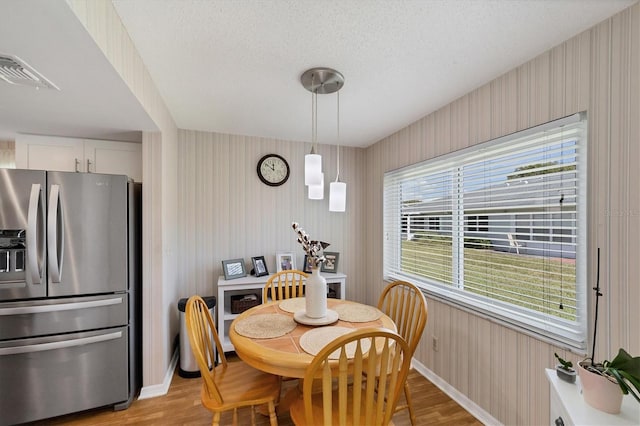 dining room with a textured ceiling and light hardwood / wood-style floors