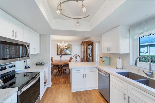 kitchen featuring sink, appliances with stainless steel finishes, kitchen peninsula, white cabinets, and a raised ceiling