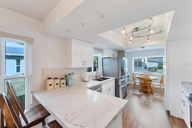 kitchen featuring a raised ceiling, light stone countertops, white cabinets, and dark hardwood / wood-style flooring