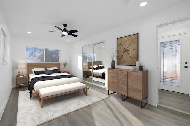 bedroom featuring ceiling fan, a closet, light hardwood / wood-style floors, and multiple windows