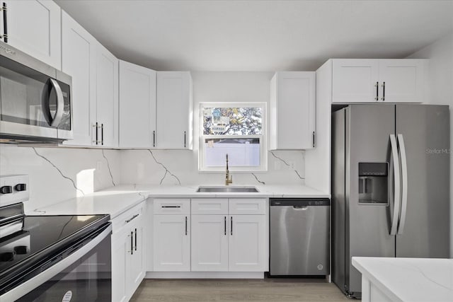 kitchen featuring appliances with stainless steel finishes, tasteful backsplash, sink, white cabinets, and light stone counters