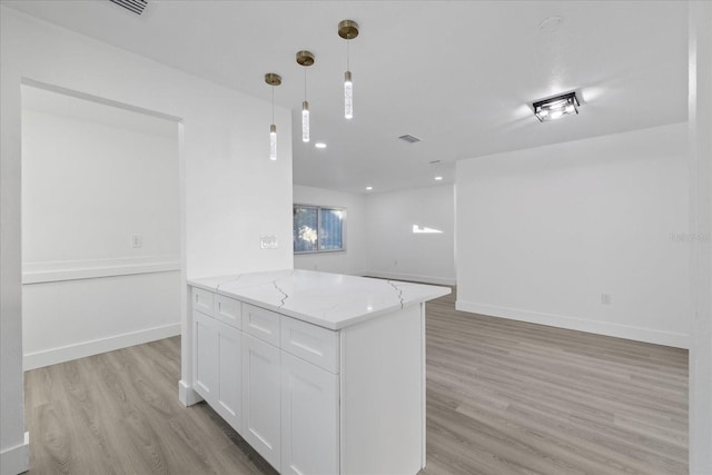 kitchen with light hardwood / wood-style flooring, white cabinets, light stone counters, and decorative light fixtures