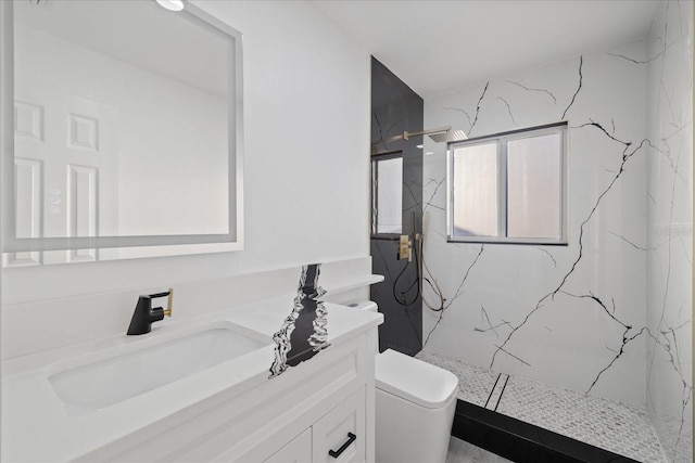 bathroom with tiled shower, vanity, and toilet