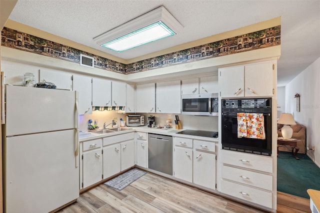 kitchen with white cabinetry, sink, light hardwood / wood-style floors, and black appliances