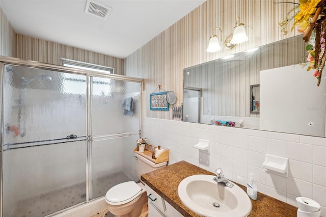 bathroom featuring toilet, tile walls, vanity, and walk in shower