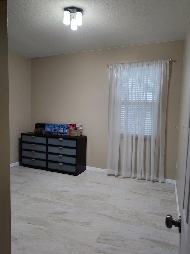 bedroom with a textured ceiling and baseboards