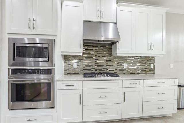 kitchen with white cabinetry, tasteful backsplash, range hood, and appliances with stainless steel finishes