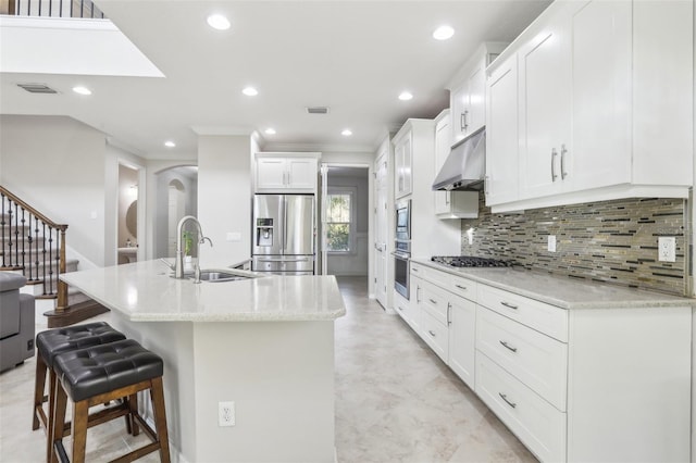 kitchen with an island with sink, appliances with stainless steel finishes, sink, and white cabinets