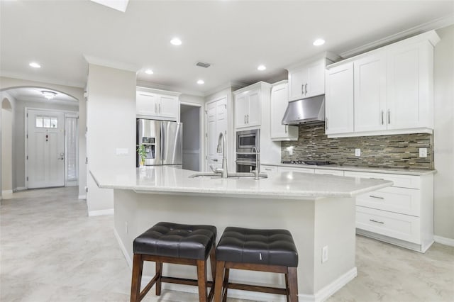 kitchen featuring white cabinetry, a kitchen bar, stainless steel appliances, and a center island with sink