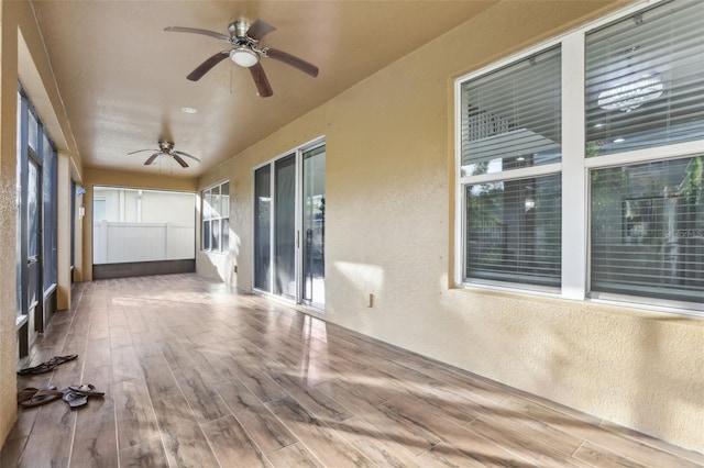 unfurnished sunroom featuring ceiling fan