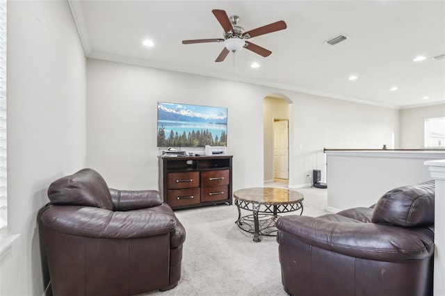 carpeted living room with crown molding and ceiling fan