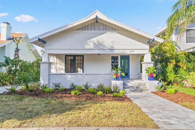 bungalow-style house featuring covered porch and a front lawn