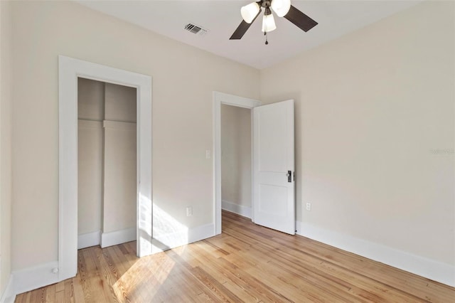 unfurnished bedroom with light wood-type flooring, ceiling fan, and a closet