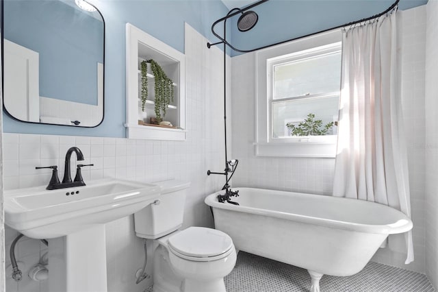 bathroom with tile patterned floors, toilet, and tile walls