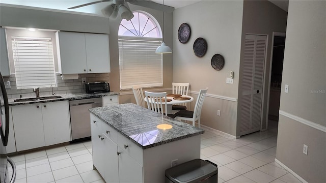 kitchen featuring sink, white cabinetry, a center island, stainless steel dishwasher, and dark stone counters