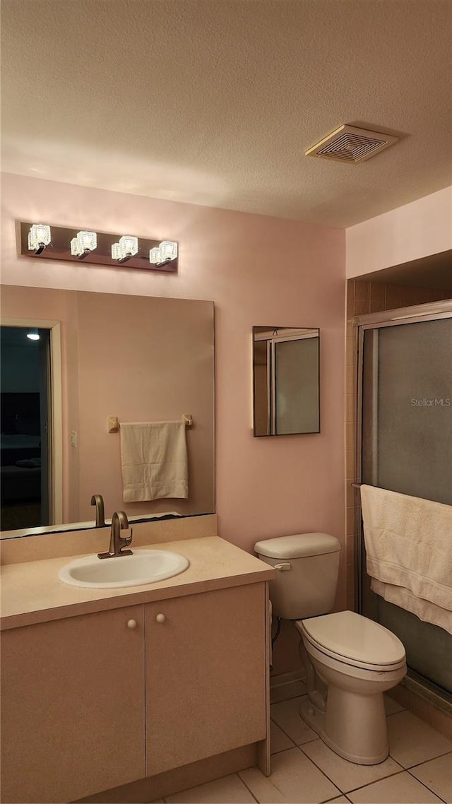 bathroom featuring vanity, toilet, a shower with door, tile patterned floors, and a textured ceiling