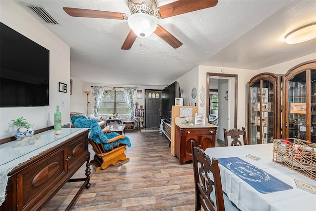 dining area with ceiling fan, light hardwood / wood-style flooring, and a textured ceiling