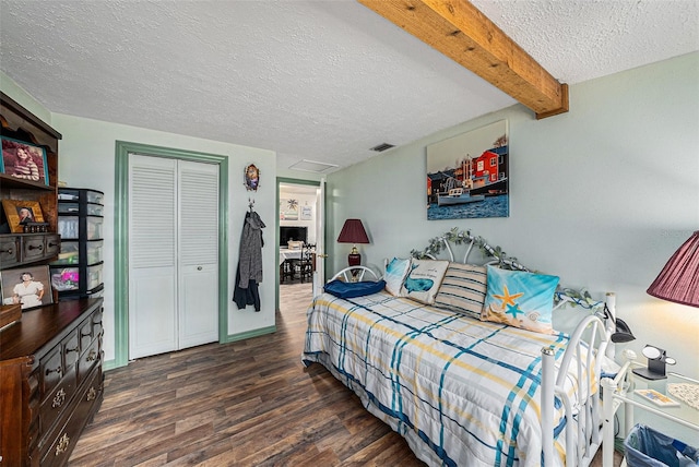 bedroom with beamed ceiling, dark wood-type flooring, a textured ceiling, and a closet