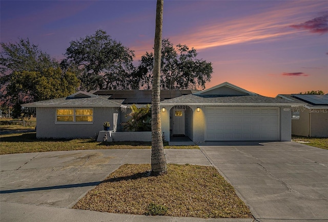 ranch-style home featuring a garage and solar panels