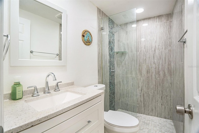 bathroom with vanity, tiled shower, and toilet