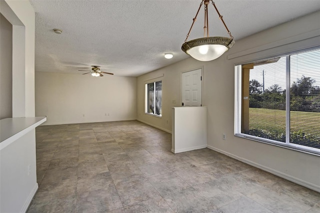 unfurnished living room with ceiling fan, a healthy amount of sunlight, and a textured ceiling