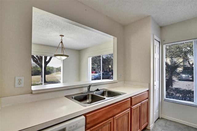 kitchen featuring pendant lighting, sink, dishwasher, and a textured ceiling