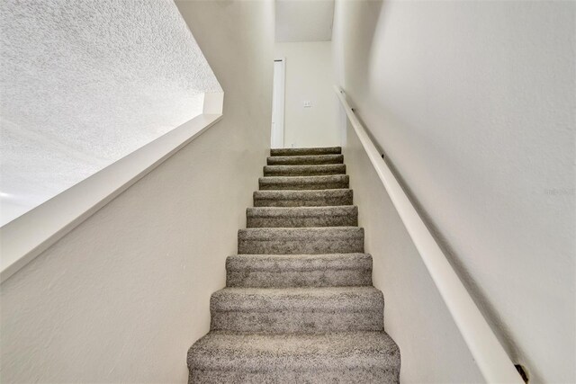 staircase featuring a textured ceiling