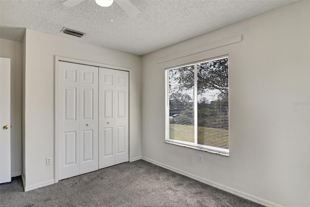 unfurnished bedroom with ceiling fan, carpet floors, a textured ceiling, and a closet