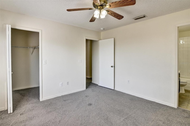 unfurnished bedroom featuring light colored carpet, ensuite bath, a closet, and a textured ceiling