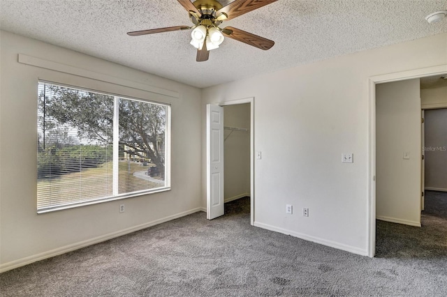 unfurnished bedroom featuring a walk in closet, carpet, ceiling fan, a textured ceiling, and a closet