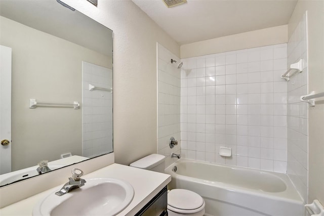 full bathroom with tiled shower / bath, vanity, and toilet