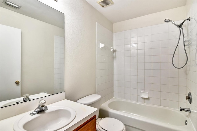 full bathroom featuring tiled shower / bath combo, vanity, and toilet