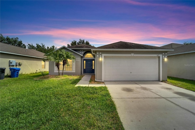 single story home featuring a garage and a yard