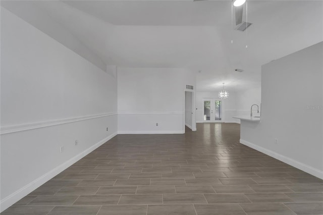 unfurnished living room featuring sink and a chandelier