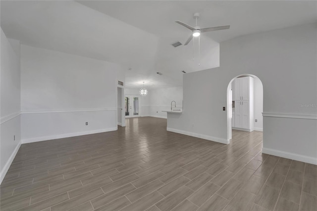 unfurnished living room with vaulted ceiling and ceiling fan with notable chandelier