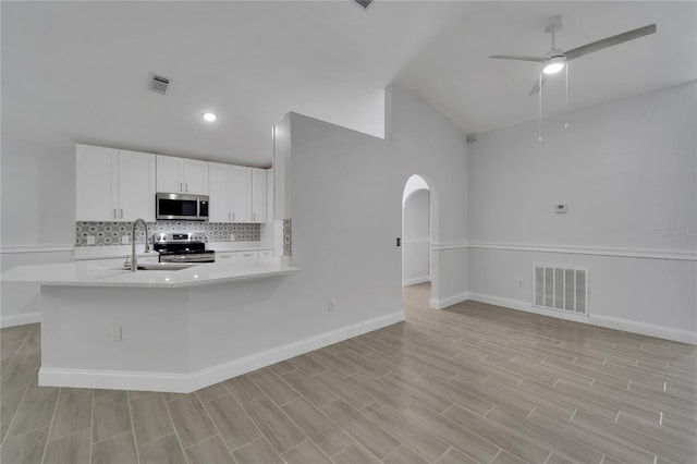 kitchen with sink, white cabinetry, kitchen peninsula, stainless steel appliances, and decorative backsplash