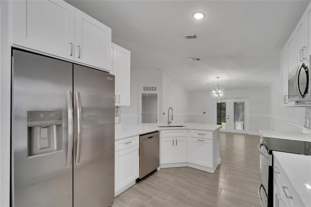 kitchen featuring appliances with stainless steel finishes, kitchen peninsula, sink, and white cabinets