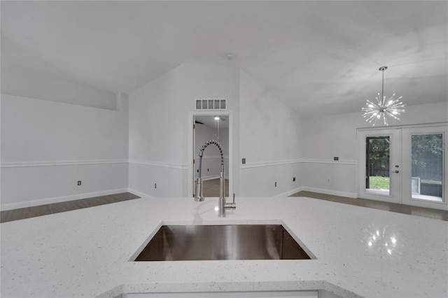 kitchen with french doors, sink, vaulted ceiling, hanging light fixtures, and light stone countertops