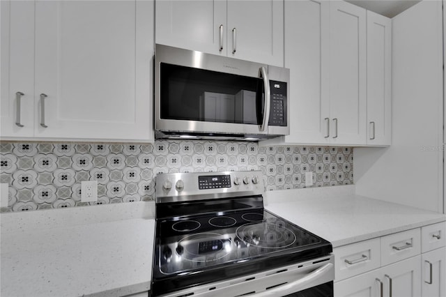 kitchen featuring white cabinetry, stainless steel appliances, light stone countertops, and backsplash